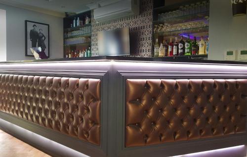 a bar with a brown leather bar bench at The Lansbury Heritage Hotel & SPA By Sunday - Canary Wharf London in London