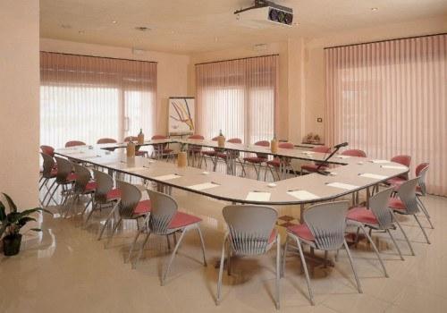 une grande salle de conférence avec une grande table et des chaises dans l'établissement Hotel La Corte, à Rubiera