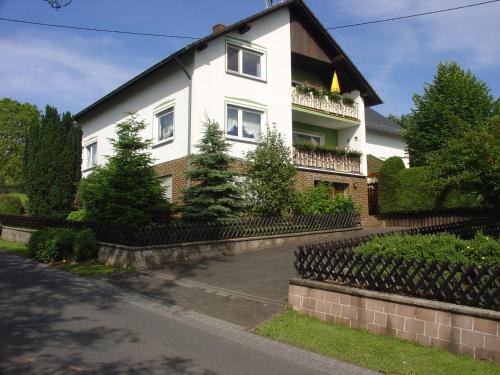 uma casa branca com uma cerca à frente. em Cosy Apartment in Wilsecker near the Forest em Kyllburg