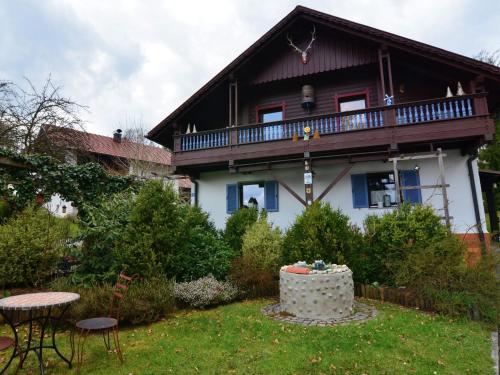 a house with a balcony and a table in the yard at Holiday home in Saldenburg with sauna in Saldenburg