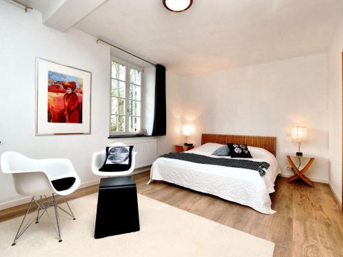 um quarto com uma cama e 2 cadeiras brancas em Charming holiday home in Ardennes and large garden em Honnay