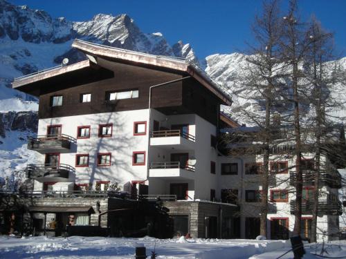 ein Gebäude im Schnee mit Bergen im Hintergrund in der Unterkunft Belvilla by OYO Just 30m from the ski lifts in Breuil-Cervinia