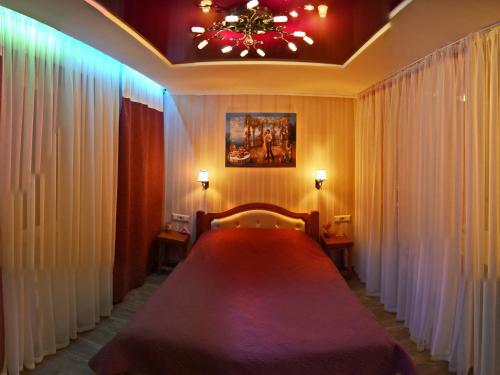 ein Schlafzimmer mit einem großen Bett mit Vorhängen und einem Kronleuchter in der Unterkunft ApartLux Chernigov in Tschernihiw
