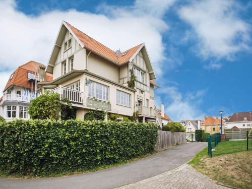 a large house with a hedge in front of it at Beautiful villa 200 metres from the sea in Koksijde