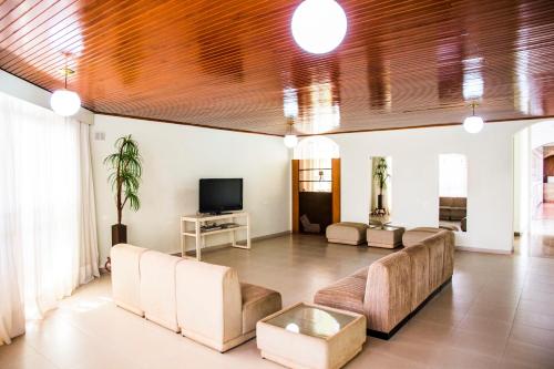 a living room with a couch and a tv at Hotel Barrocos in Goiatuba