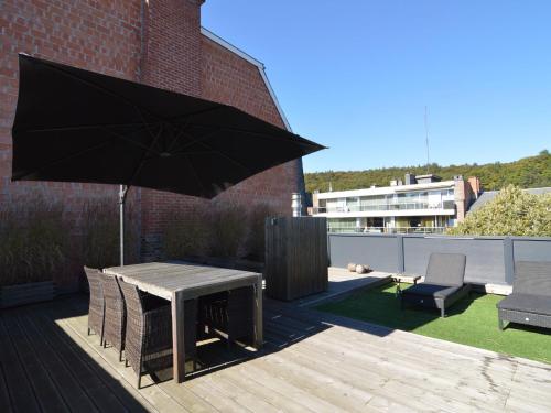 eine Holzterrasse mit einem Tisch und einem Sonnenschirm in der Unterkunft Beautiful Apartment in Spa near Casino in Spa