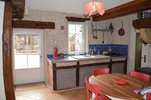 a kitchen with a table and a kitchen with blue tiles at Chambre d'hôtes Domaine de la Guinchère in LʼHôpital-le-Mercier