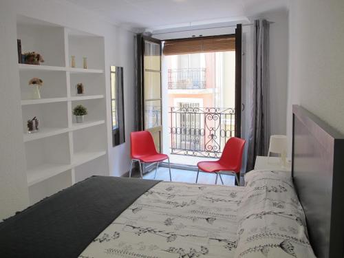 a bedroom with a bed and two red chairs at Apartamentos Romero in Alicante