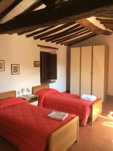 two beds in a room with red sheets at Podere Gnocchi in Rapale