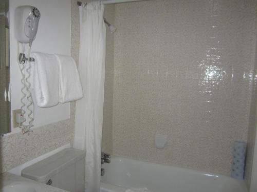 La salle de bains est pourvue d'une baignoire blanche et d'une douche. dans l'établissement Schell Motel, à Vernon