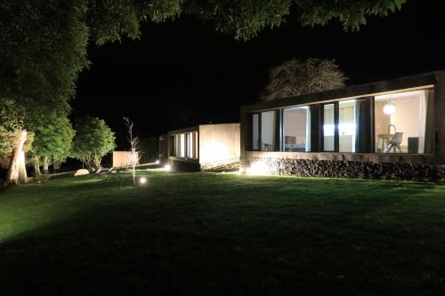 a house with lights in the yard at night at World's Nests Furnas Pods Village in Furnas