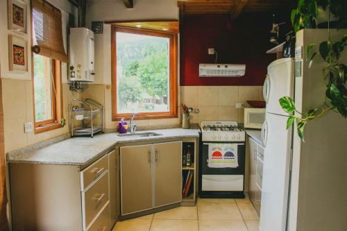 una pequeña cocina con fregadero y nevera. en Casa Pocahullo en San Martín de los Andes