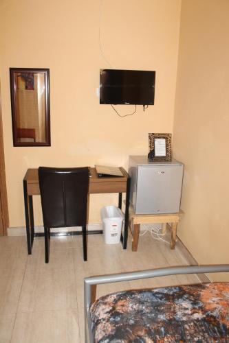 a room with a desk with a computer and a television at Jesiwa B's Little Palace in Accra
