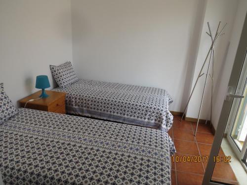 ザンブジェイラ・ド・マールにあるCasas do Zé Zambujeira do Marのベッドルーム1室(ベッド2台、ブルーランプ付)
