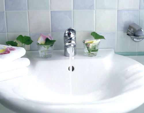 a bathroom sink with a faucet and two glasses on it at Hotel Roma in Grottammare