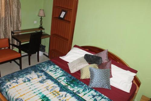 a bedroom with a bed with pillows and a desk at Jesiwa B's Little Palace in Accra