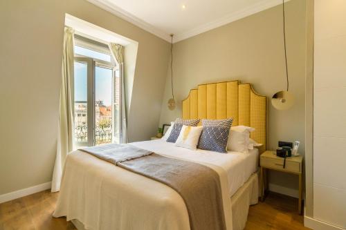 a bedroom with a large bed with a yellow headboard at Bairro Alto Suites in Lisbon