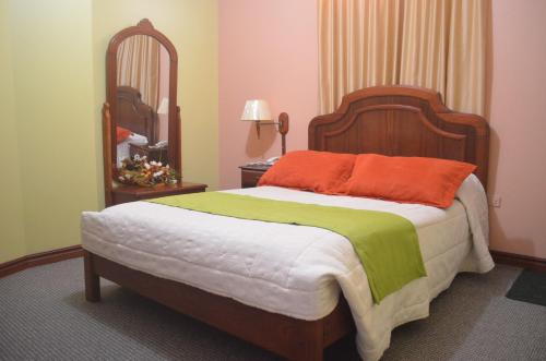a bedroom with a bed with an orange and green blanket at Hotel Betania in Zamora