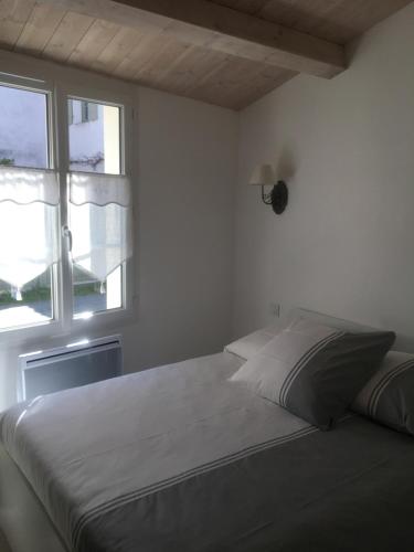 a white bedroom with a bed and a window at Locations Ile de Ré in Sainte-Marie-de-Ré