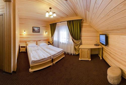 a bedroom with a large bed and a television at Forest House in Tatariv
