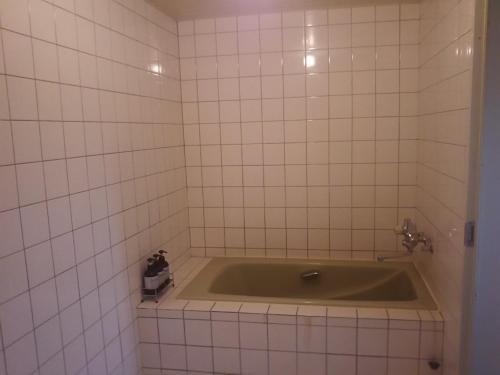 a bath tub in a bathroom with white tiles at Hotel Sting in Tokyo