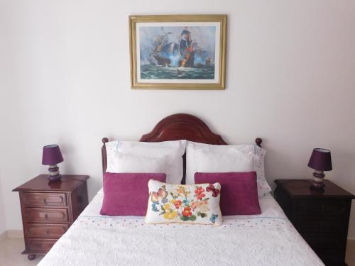 Un dormitorio con una cama con almohadas moradas y una pintura en Casa Happybella en Lagos