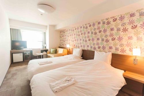 a hotel room with two beds with towels on them at Daiwa Roynet Hotel Okinawa-Kenchomae in Naha