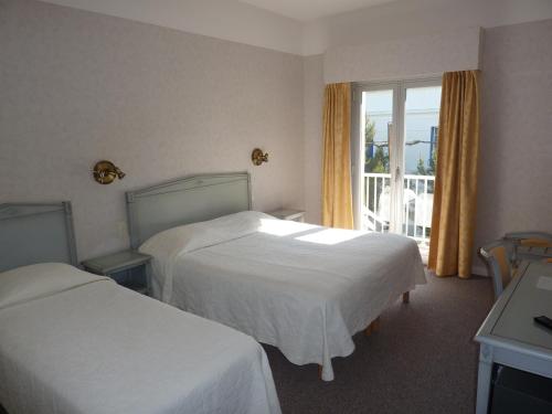 um quarto de hotel com duas camas e uma janela em Hôtel La Concorde em La Baule