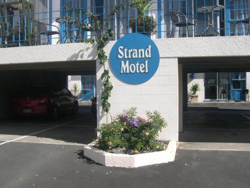 a sign for a stand motel in a parking lot at Strand Motel in Tauranga