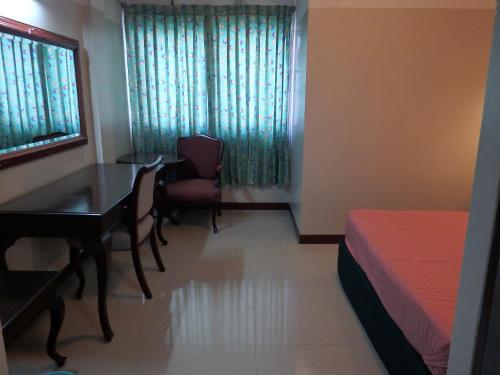 a bedroom with a table and a bed and a desk at Sakol Hotel in Nakhon Ratchasima