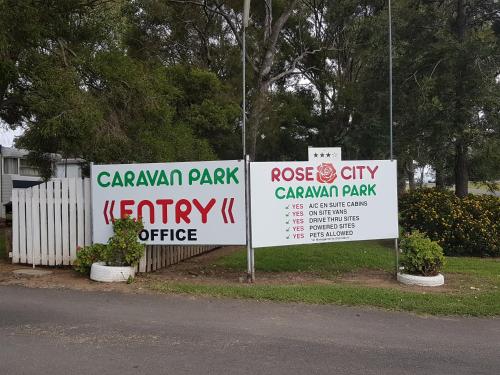 a couple of signs on the side of a road at Rose City Caravan Park in Warwick