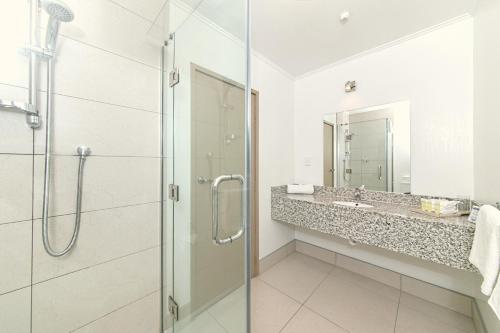 a bathroom with a glass shower and a sink at Airport Gateway Hotel in Auckland