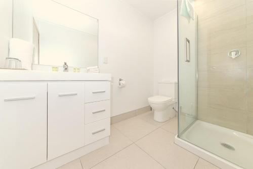 a white bathroom with a shower and a toilet at Airport Gateway Hotel in Auckland