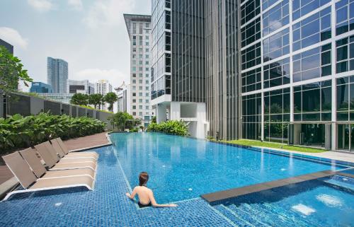 un hombre sentado en una piscina en una ciudad en Ascott Orchard Singapore en Singapur