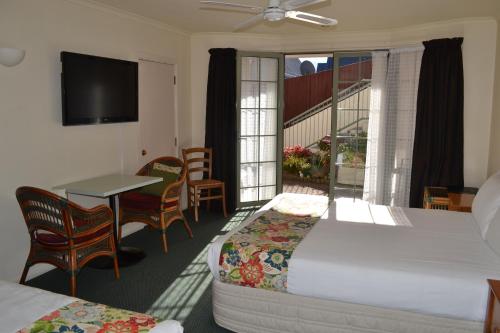 a hotel room with a bed and a table and chairs at Colonial Lodge Motel in Taupo