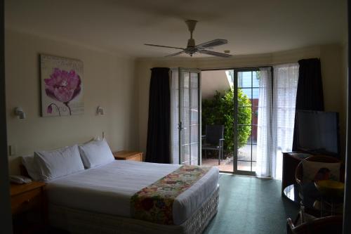 a bedroom with a bed and a sliding glass door at Colonial Lodge Motel in Taupo