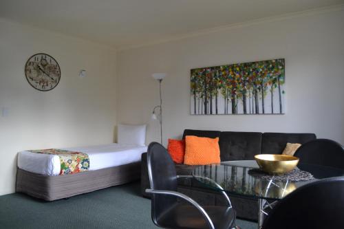 a room with a bed and a couch and a table at Colonial Lodge Motel in Taupo