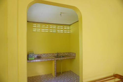a bathroom with a yellow wall with a sink at T and T house in Ko Phayam