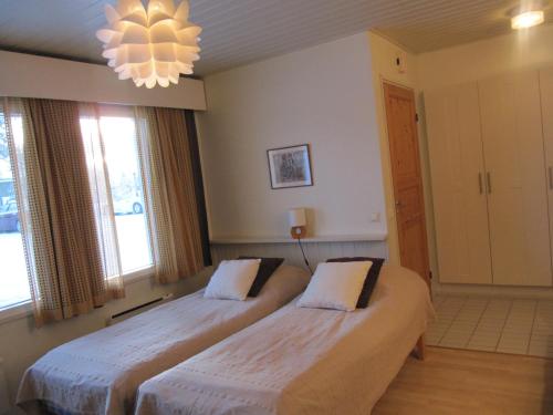two beds in a room with windows and a chandelier at Lapin Kutsu Apartments in Saariselka