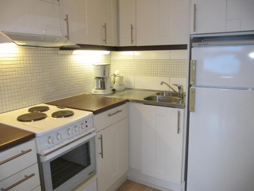 Lapin Kutsu Apartments في ساريسيلكا: مطبخ فيه دواليب بيضاء وثلاجة بيضاء