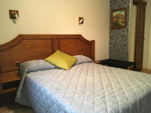 1 cama con cabecero de madera y almohada amarilla en Aux Vieux Arceaux, en Mercuer