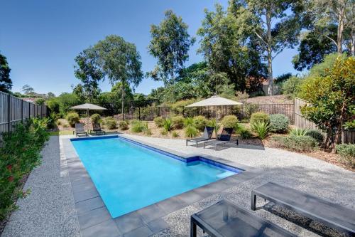 una piscina en un patio con bancos y sombrillas en Punthill Norwest, en Baulkham Hills