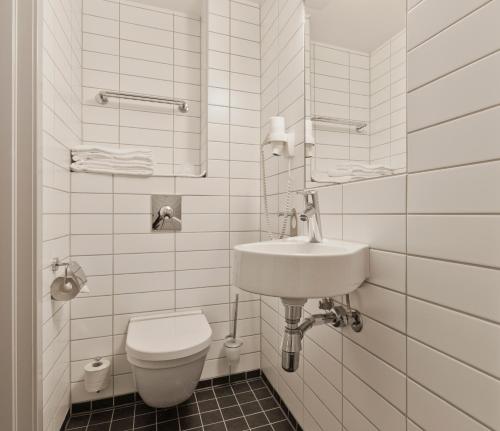 a white bathroom with a toilet and a sink at MediInn Hotel Oslo in Oslo