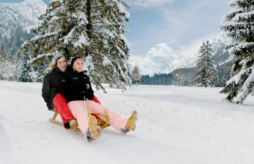 two women sitting on a sled in the snow at Hotel Achentalerhof in Achenkirch