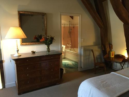 a bedroom with a dresser with a lamp and a mirror at Maison d'Hôtes Chandon de Briailles in Savigny-lès-Beaune