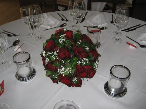 a table with a bouquet of red roses on it at Seminar- & Erlebnishotel RömerTurm in Filzbach