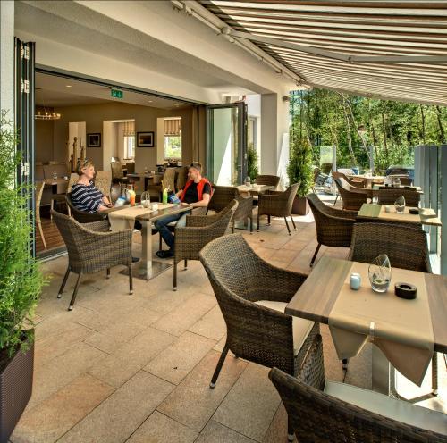 two people sitting in a restaurant with tables and chairs at Hotel Haus am Meer in Graal-Müritz