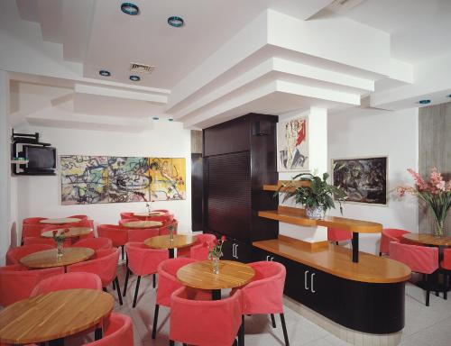 リド・ディ・イエゾロにあるHotel Wallyの木製テーブルと赤い椅子が備わるレストラン