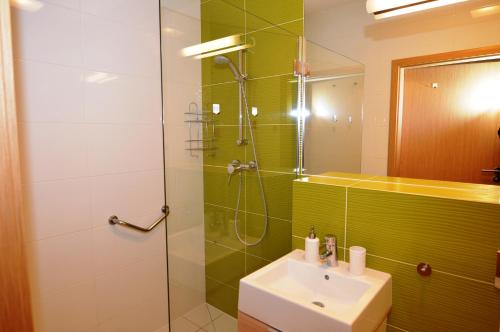 a bathroom with a sink and a shower with green tiles at Apartament Czternastka in Świnoujście