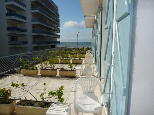 Un balcón con una silla blanca y vistas al océano. en Hôtel La Concorde en La Baule